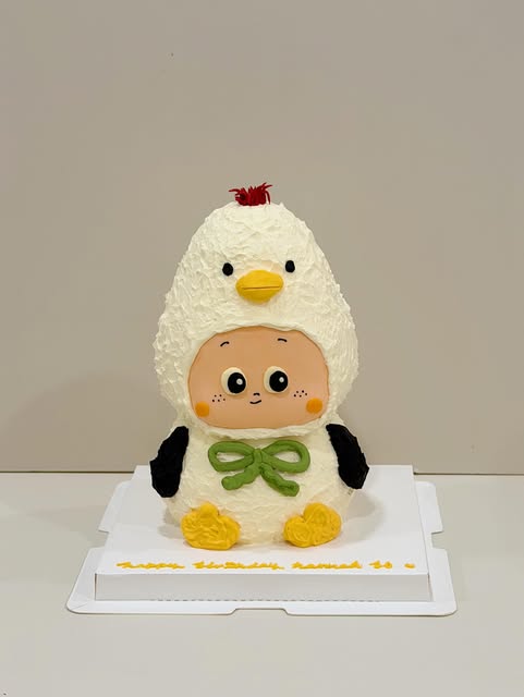 Chicken-costume character cake with a green bow and yellow feet