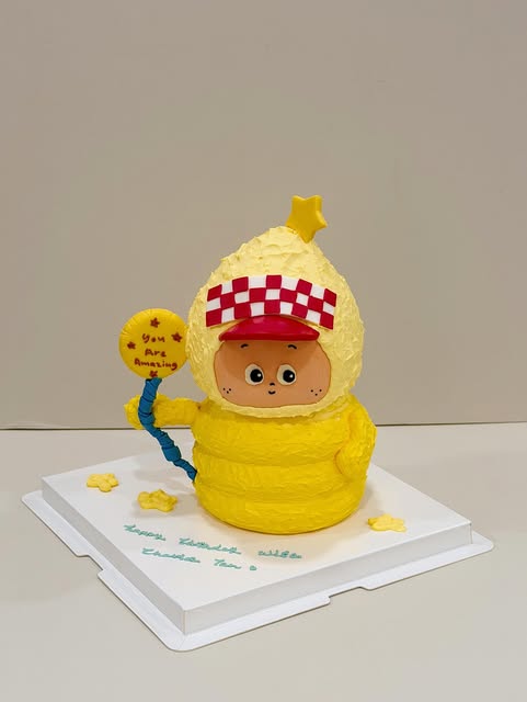Yellow character cake in a checkered cap holding a fondant star sign