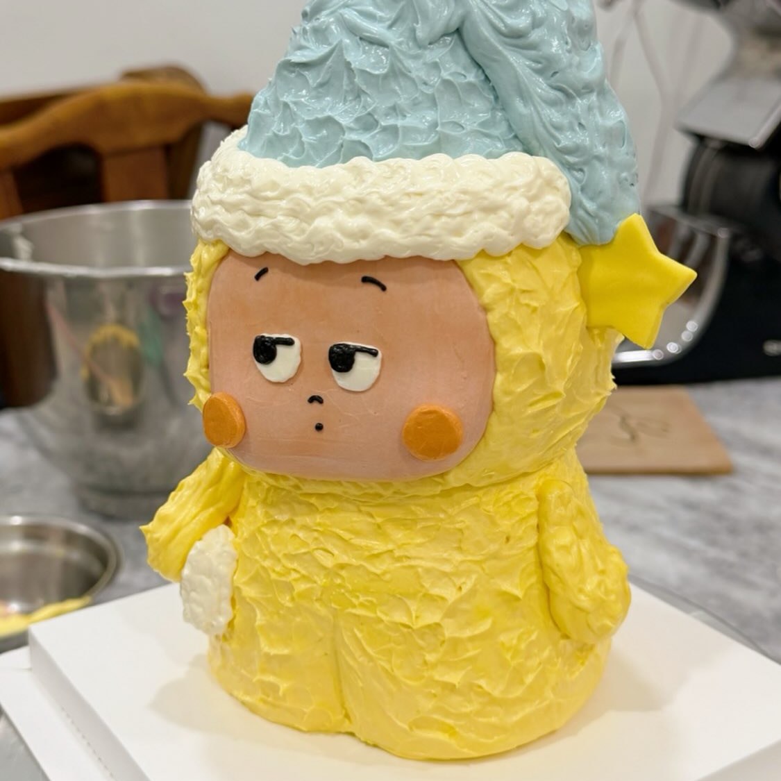 Yellow character cake with a blue nightcap and star charm