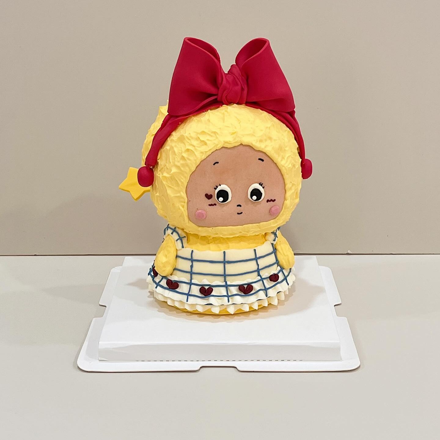 Yellow hooded character cake with a red bow and checkered dress