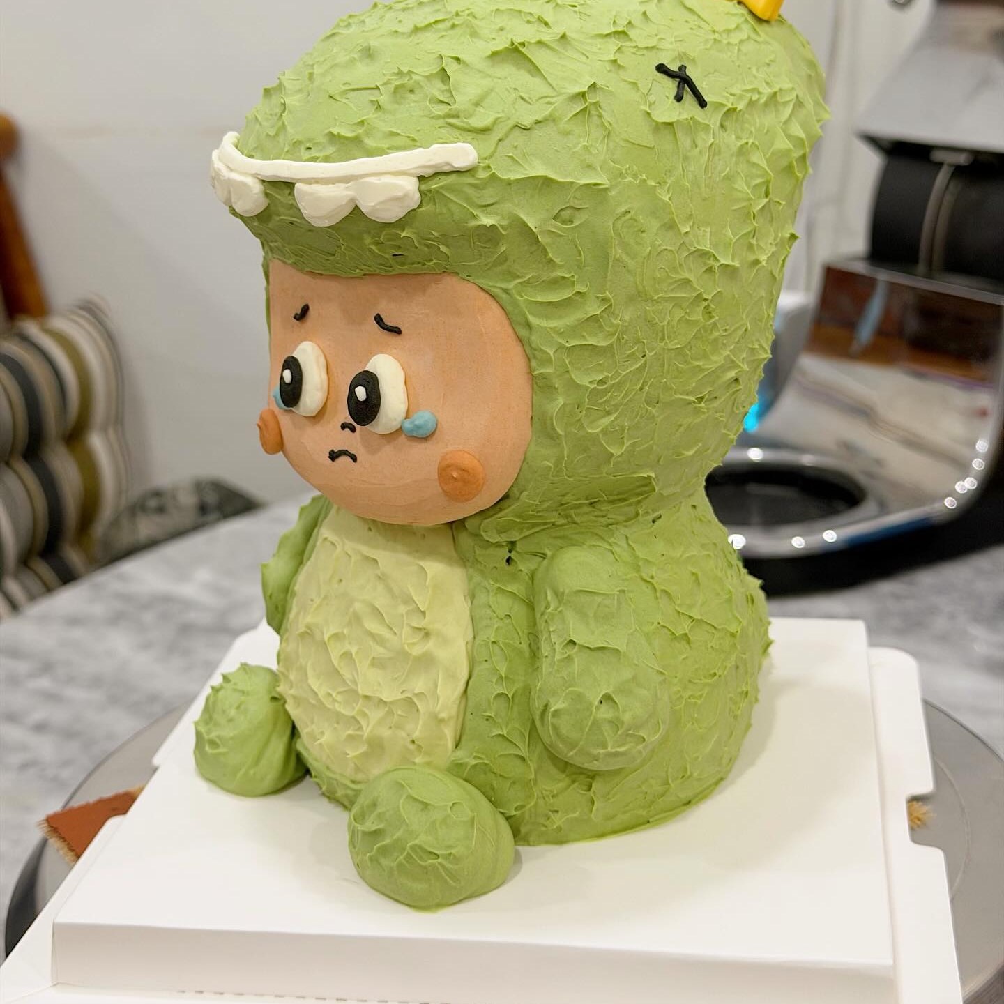Green bunny-eared character cake with a star topper