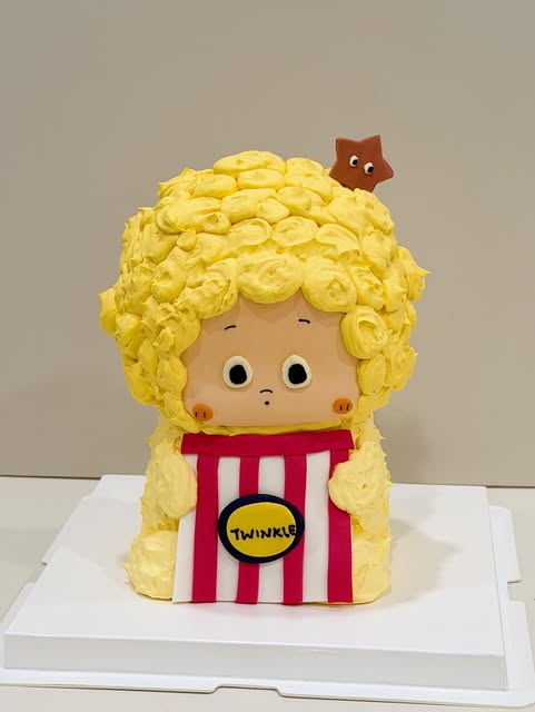 Popcorn-themed character cake with piped yellow buttercream curls and a TWINKLE label
