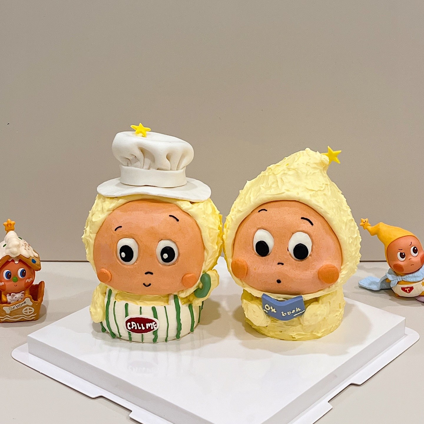 Twin star-topped character cakes, one wearing a chef hat