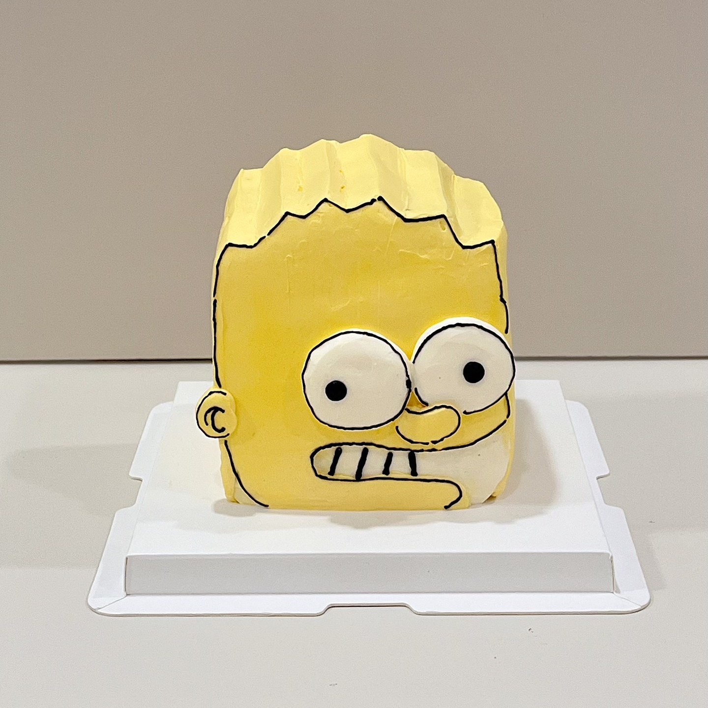 Yellow spiky-haired character cake with bold cartoon eyes