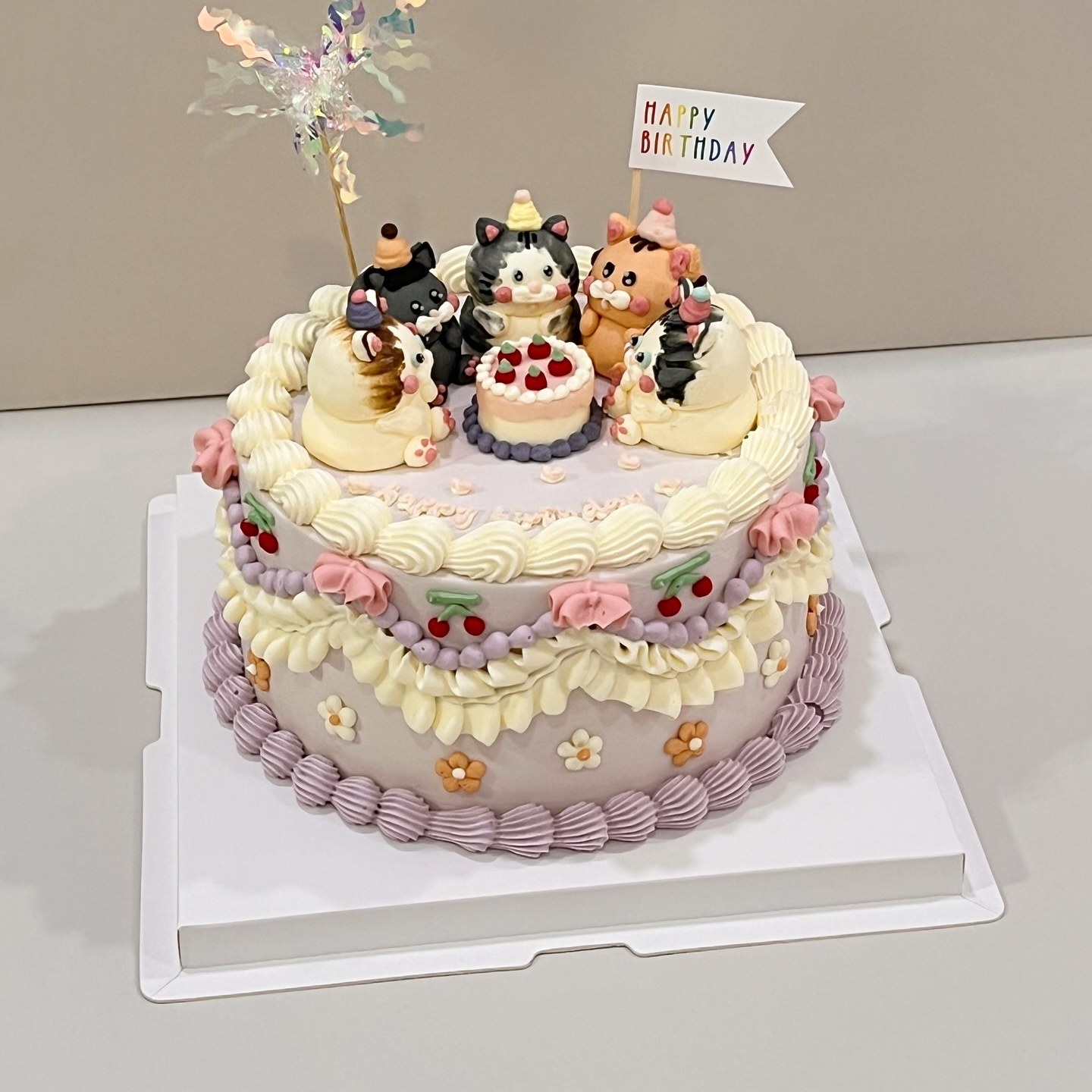Purple cake with kitten figurines, cherries and floral piping