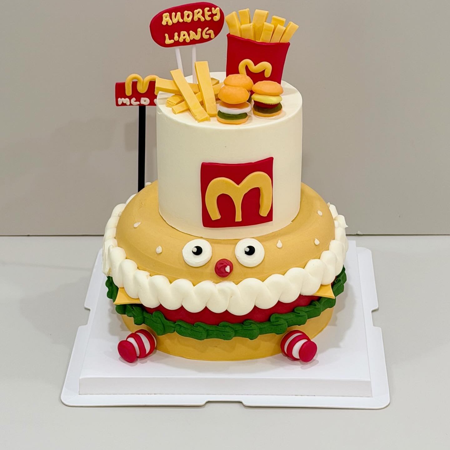 Two-tier burger-themed cake with fries and burger toppers and branded packaging