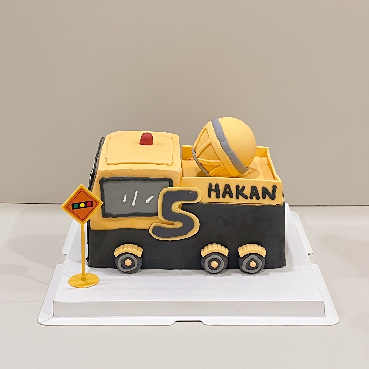 Black and yellow toy truck cake with a road sign, personalised with a name and age
