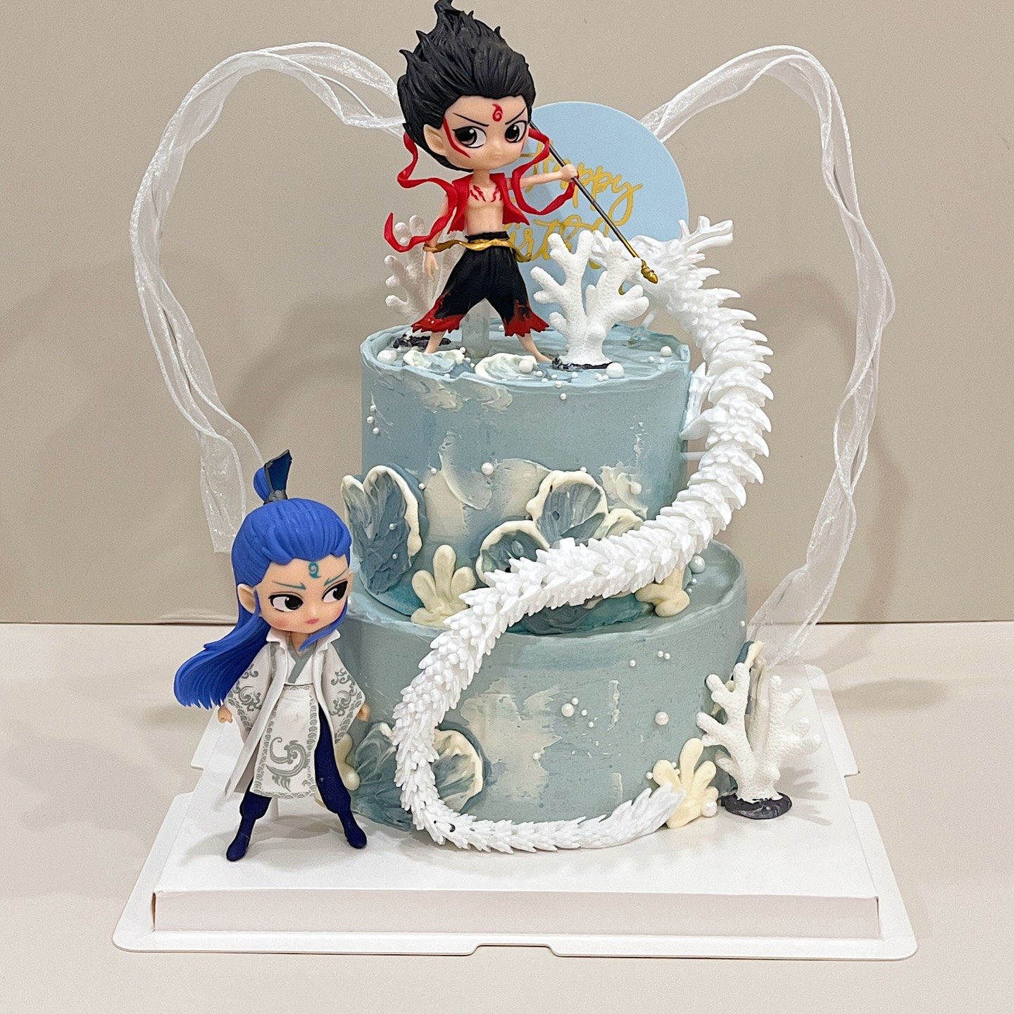 Two-tier cake with dragon detailing and character figurines on top