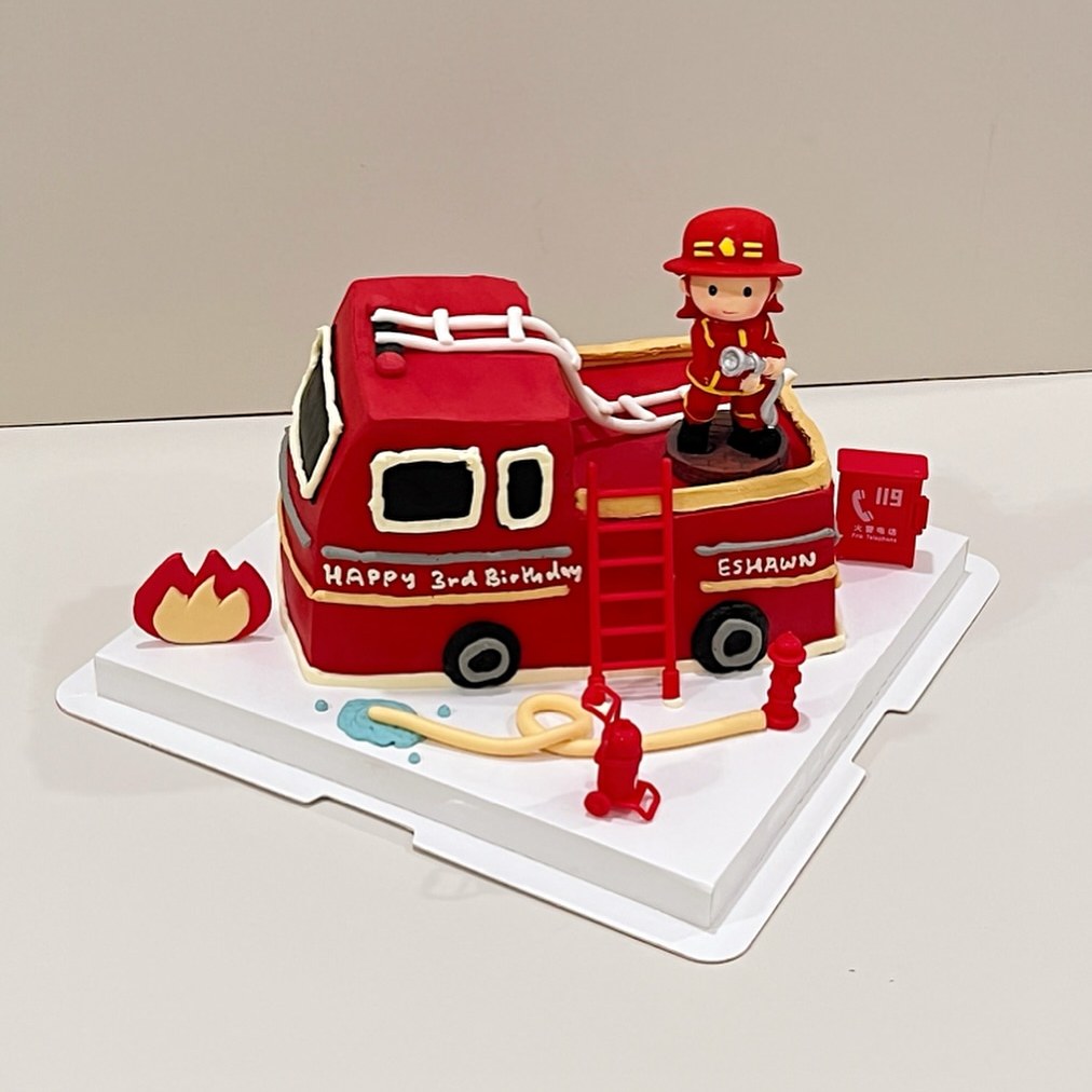 Red fire truck cake with a firefighter figurine and hose details