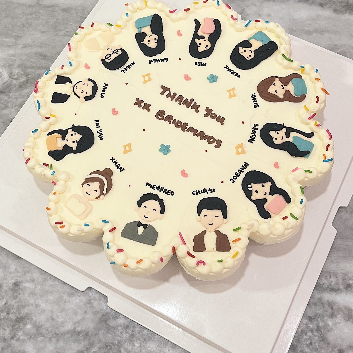 Flower-shaped flat-lay cake with hand-drawn bridesmaid portraits and a thank-you message