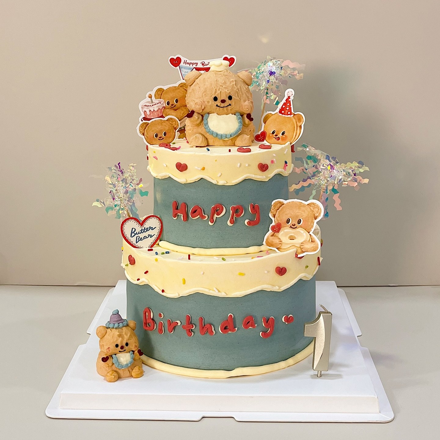Two-tier cake with bear character figurines and a Happy Birthday message
